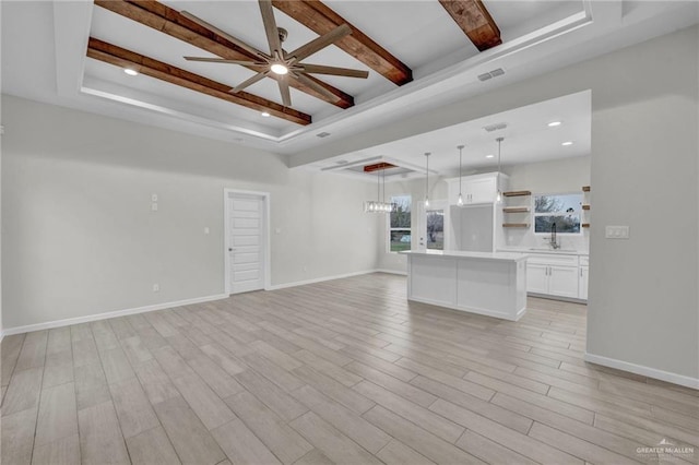 unfurnished living room featuring light wood-style flooring, a raised ceiling, and beam ceiling