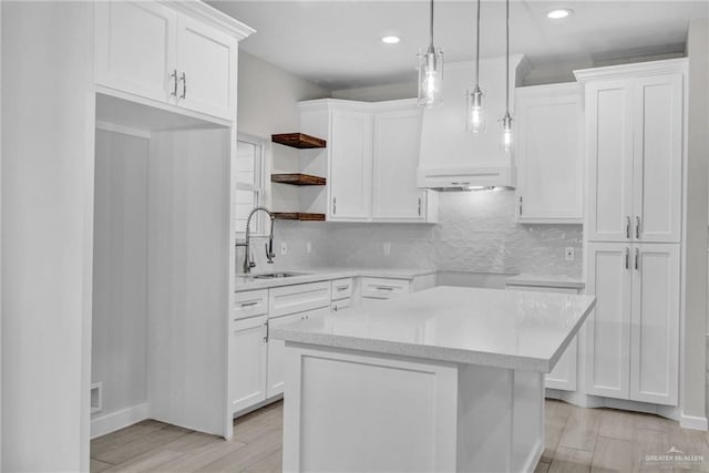 kitchen with pendant lighting, open shelves, light countertops, white cabinets, and a sink