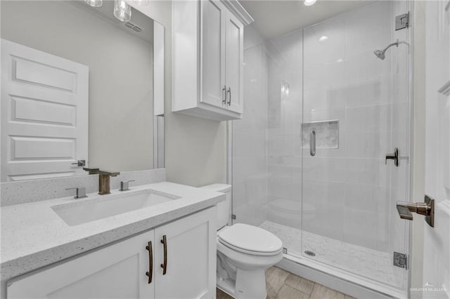 bathroom featuring toilet, a shower stall, visible vents, and vanity