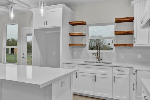 kitchen with a sink, white cabinets, a wealth of natural light, open shelves, and decorative light fixtures