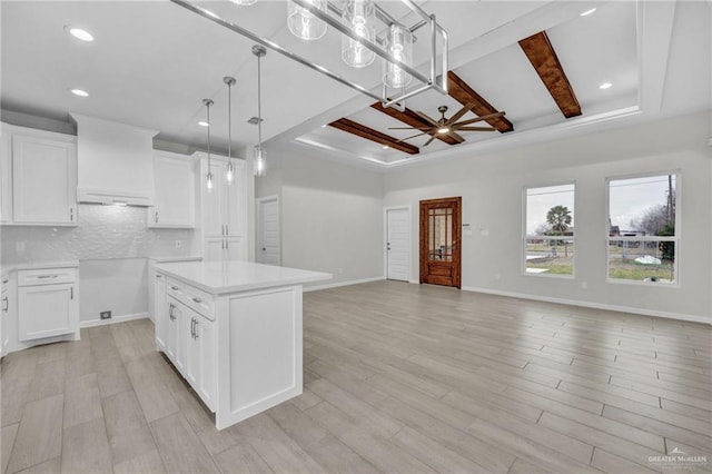 kitchen with white cabinets, a kitchen island, open floor plan, light countertops, and backsplash