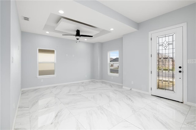 unfurnished room with ceiling fan and a raised ceiling