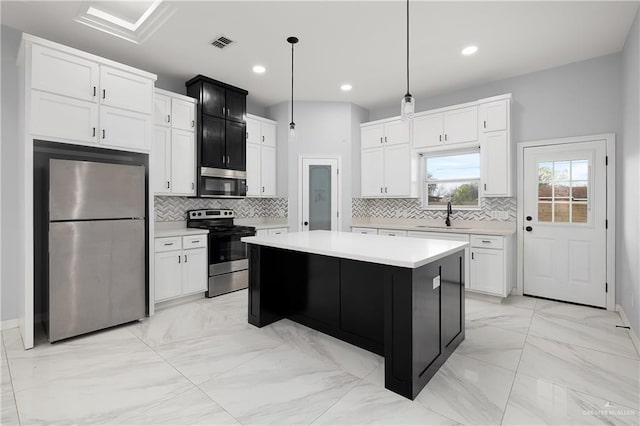 kitchen featuring white cabinetry, stainless steel appliances, a center island, decorative light fixtures, and sink