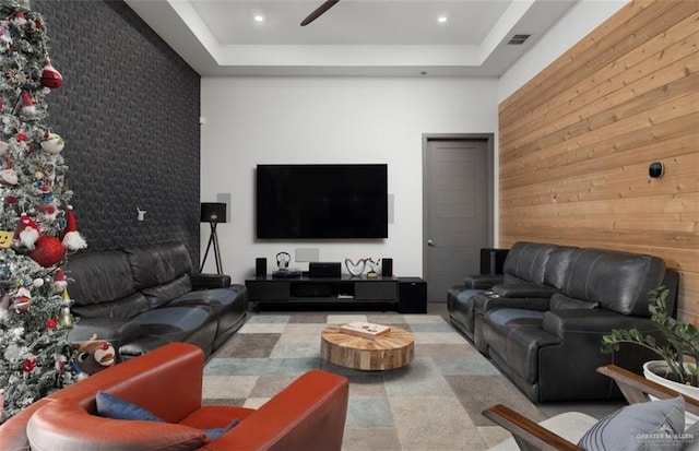 living room with a raised ceiling and wooden walls