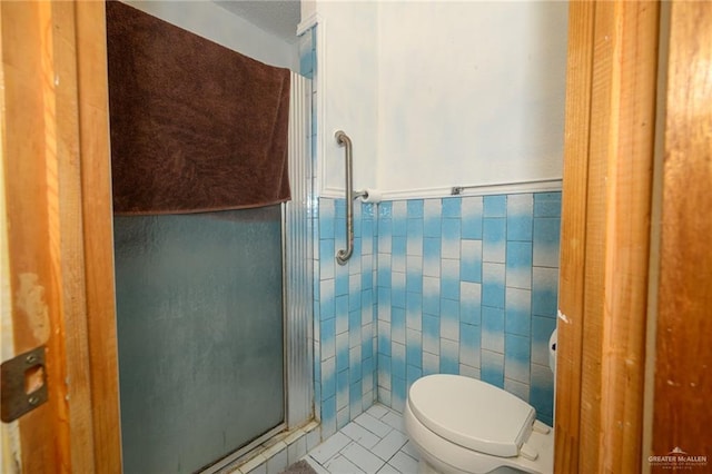 bathroom featuring tile patterned flooring, a shower stall, a wainscoted wall, toilet, and tile walls