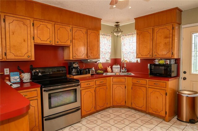 kitchen with electric range, a sink, a textured ceiling, brown cabinetry, and black microwave