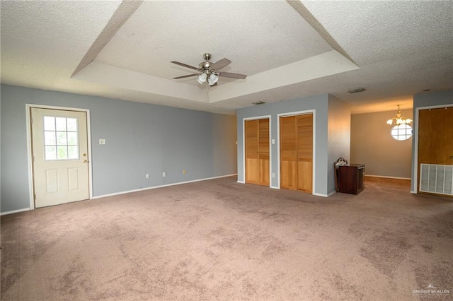 interior space with a tray ceiling, carpet floors, two closets, and visible vents