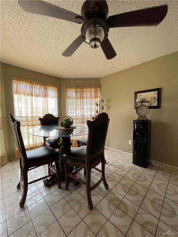 kitchen featuring ceiling fan, black microwave, a peninsula, freestanding refrigerator, and brown cabinetry