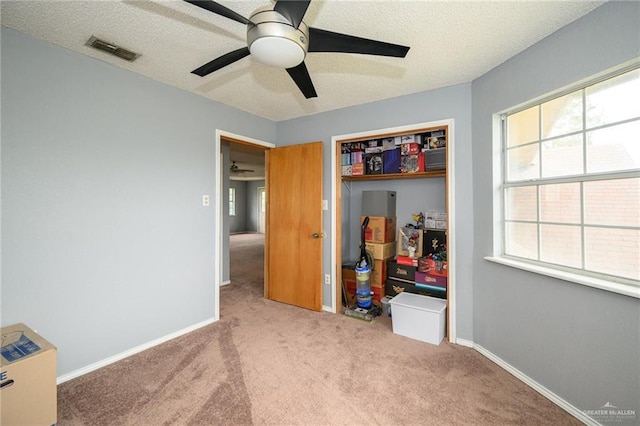 carpeted bedroom with visible vents, ceiling fan, baseboards, a closet, and a textured ceiling