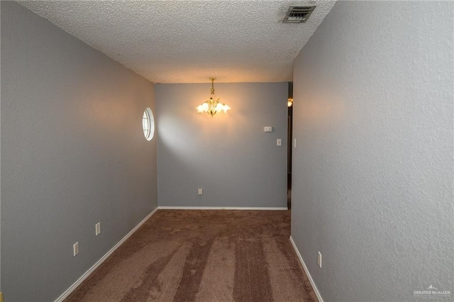 empty room with visible vents, baseboards, carpet flooring, a notable chandelier, and a textured ceiling