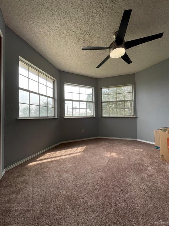 carpeted spare room featuring a ceiling fan, baseboards, and a textured ceiling