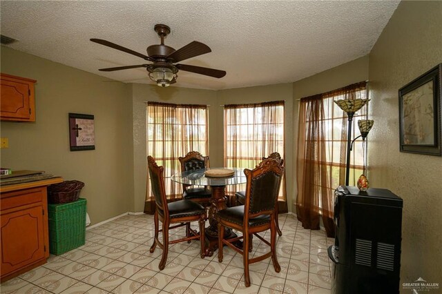 dining space with visible vents, a ceiling fan, baseboards, and a textured ceiling