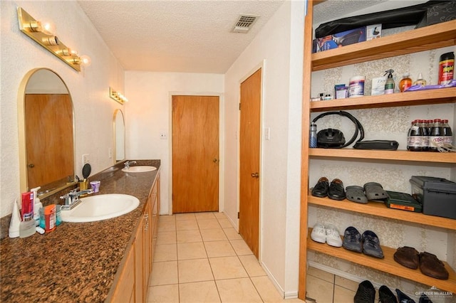 bathroom featuring a textured ceiling, visible vents, tile patterned flooring, and a sink