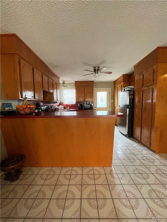 kitchen featuring visible vents, brown cabinets, stainless steel electric stove, and a peninsula