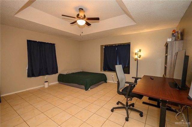 bedroom featuring a tray ceiling, baseboards, and a textured ceiling
