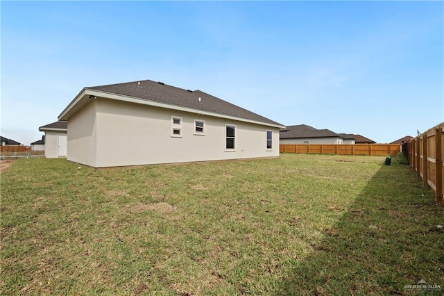 rear view of property featuring a fenced backyard, stucco siding, and a yard