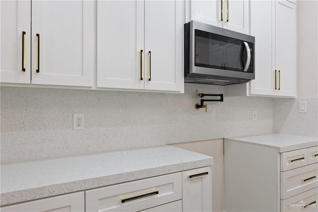 kitchen featuring white cabinetry, light stone counters, and decorative backsplash