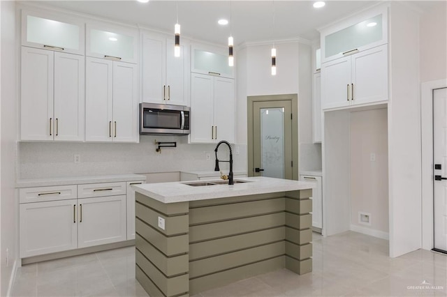 kitchen featuring light tile patterned flooring, sink, decorative light fixtures, a center island with sink, and white cabinets