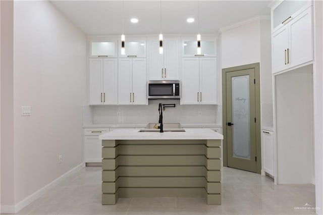 kitchen featuring tasteful backsplash, light stone counters, pendant lighting, a kitchen island with sink, and white cabinets