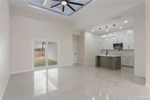 kitchen with white cabinetry, sink, ceiling fan, and decorative light fixtures