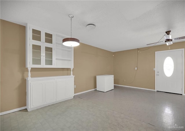 unfurnished living room with a textured ceiling and ceiling fan