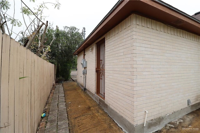 view of side of home featuring brick siding and fence