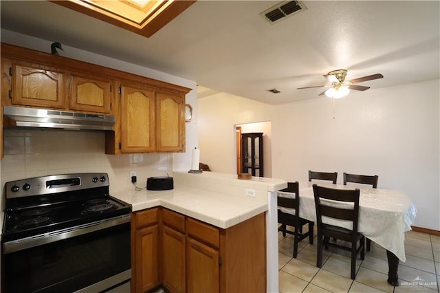 kitchen featuring under cabinet range hood, a peninsula, visible vents, light countertops, and stainless steel range with electric stovetop