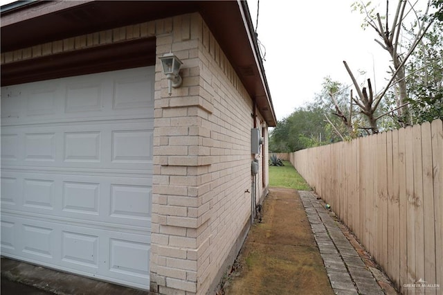 view of property exterior featuring a garage, brick siding, and fence