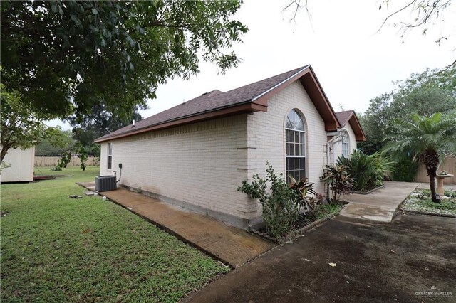 view of property exterior with brick siding, a lawn, and central AC unit