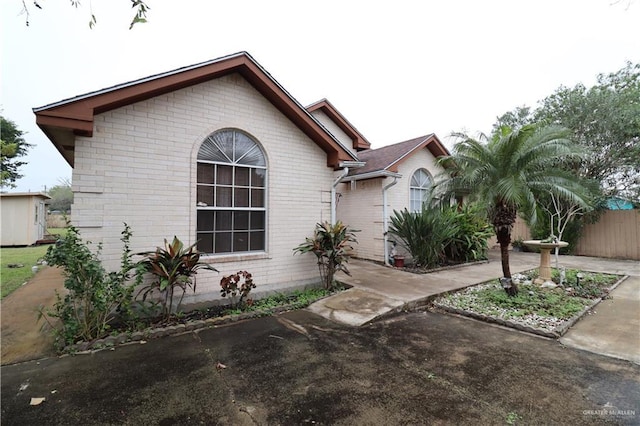 view of front of property featuring brick siding and fence