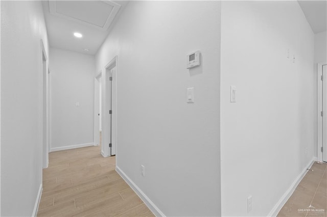 hallway with recessed lighting, light wood-type flooring, attic access, and baseboards