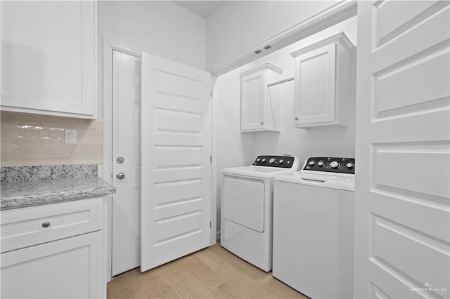 laundry room with cabinet space, light wood-style flooring, and independent washer and dryer