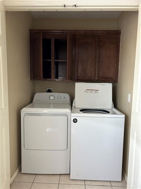 washroom with cabinets, separate washer and dryer, and light tile patterned flooring