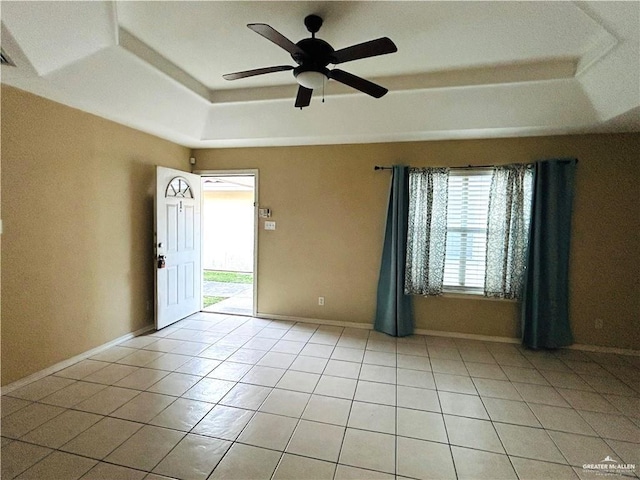 tiled spare room featuring a raised ceiling and ceiling fan