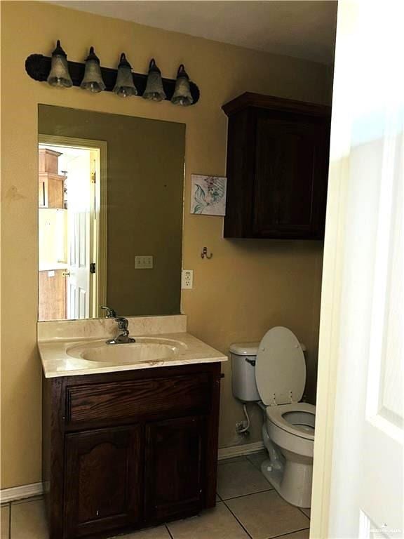 bathroom with toilet, vanity, and tile patterned floors