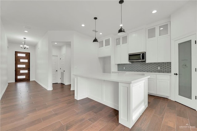 kitchen with a center island, white cabinets, hanging light fixtures, tasteful backsplash, and dark hardwood / wood-style flooring