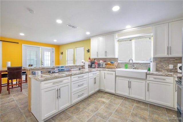 kitchen with kitchen peninsula, white cabinets, and sink