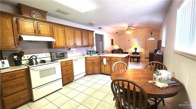2434 Starling Cir E, Palmview, TX 78572 - kitchen with brown cabinetry, light tile patterned floors, a peninsula, under cabinet range hood, and white appliances