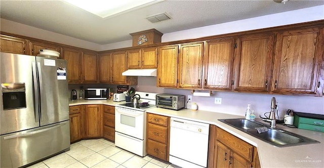 2434 Starling Cir E, Palmview, TX 78572 - kitchen with brown cabinetry, a sink, under cabinet range hood, and white appliances