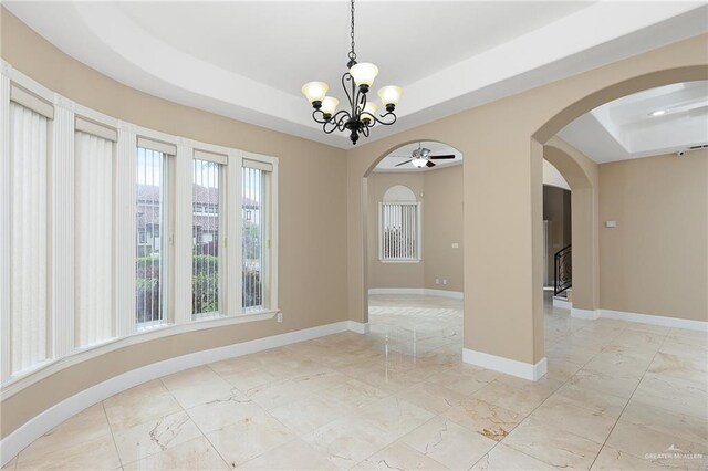 spare room with a raised ceiling and ceiling fan with notable chandelier