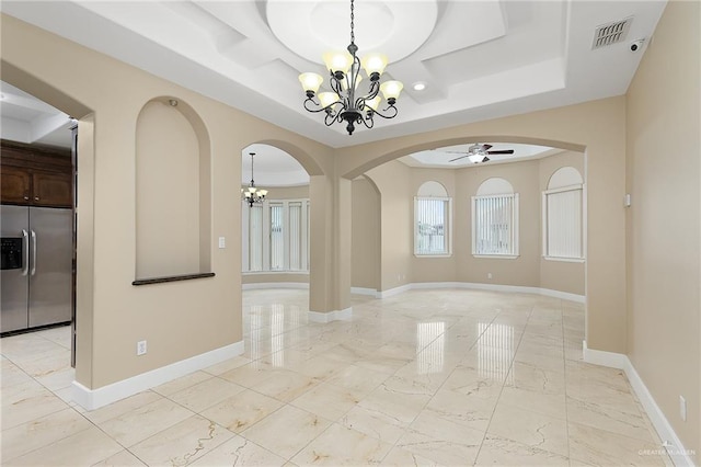 unfurnished dining area with a raised ceiling and ceiling fan with notable chandelier