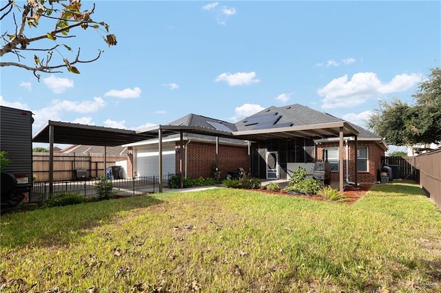 back of property with a sunroom, a garage, and a yard