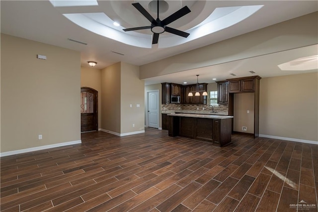 kitchen with ceiling fan, a center island, dark hardwood / wood-style flooring, pendant lighting, and dark brown cabinets