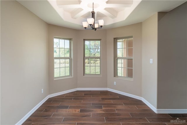 empty room featuring dark hardwood / wood-style flooring, a tray ceiling, and a notable chandelier