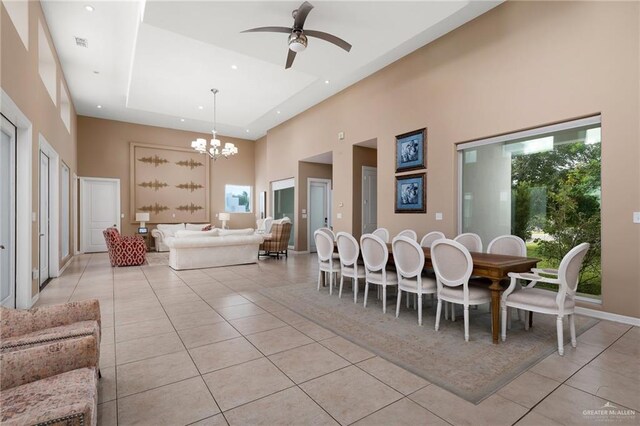 tiled dining room with a raised ceiling, a towering ceiling, and ceiling fan with notable chandelier