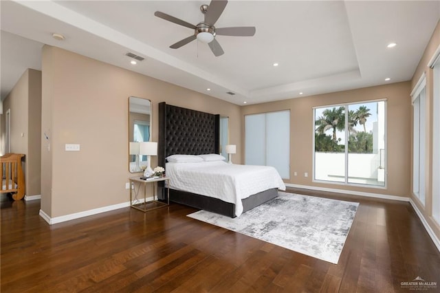 bedroom featuring a raised ceiling, ceiling fan, and dark hardwood / wood-style flooring