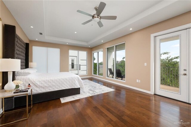 bedroom featuring a tray ceiling, access to exterior, ceiling fan, and hardwood / wood-style flooring