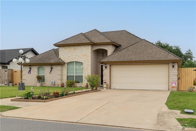 1014 Emerald Dr, Weslaco, TX 78599 - french country style house featuring stone siding, driveway, a garage, and roof with shingles