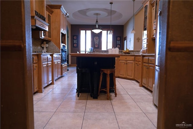 kitchen featuring a breakfast bar, a center island, oven, hanging light fixtures, and light tile patterned floors