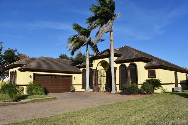 mediterranean / spanish house featuring a garage and a front lawn